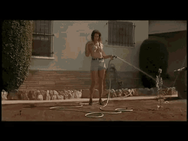 a woman in shorts is holding a hose in her hand .