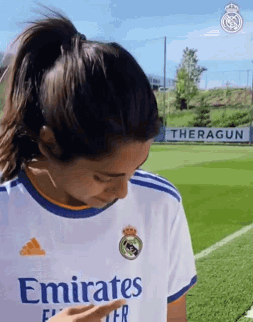 a woman wearing a white emirates shirt is pointing