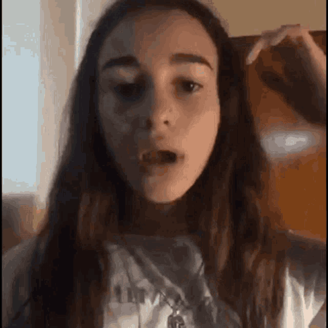 a girl with long hair is making a funny face while holding her hair .