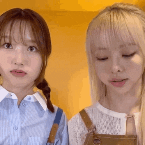 two young women are standing next to each other with their eyes closed and making funny faces .