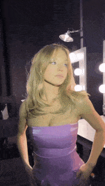 a woman in a strapless purple dress is standing in front of a mirror
