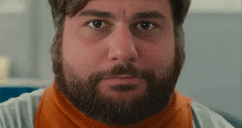 a close up of a man with a beard wearing an orange scarf .