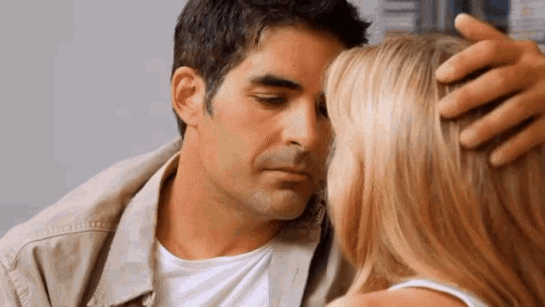 a man kissing a woman on the forehead with his hand on her head