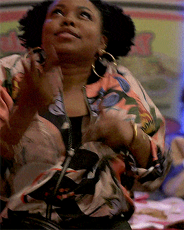 a woman wearing a floral jacket and hoop earrings applauds