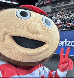 a mascot giving a peace sign in front of a sign that says erizc