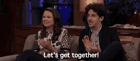 a man and a woman are sitting on a couch talking to each other .