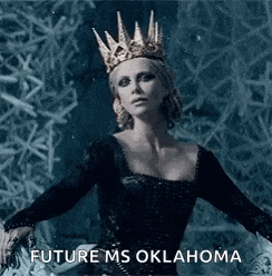 a woman wearing a crown and a black dress is standing in front of a frozen wall .