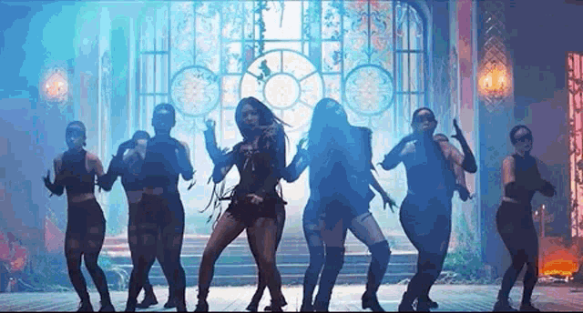 a group of women are dancing in a dark room in front of a window .
