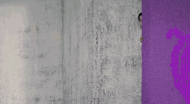 a woman peeking out of a purple wall