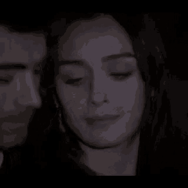 a man and a woman are looking into each other 's eyes in a dark room .