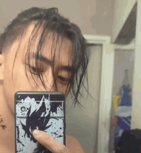 a man taking a picture of himself with a cell phone with a dragon ball z cover