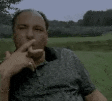 a man is smoking a cigar while sitting on a grassy field .