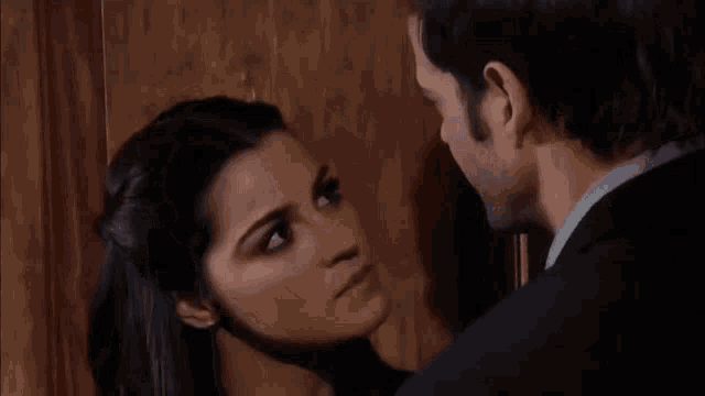 a man in a suit and a woman in a blue shirt are looking at each other