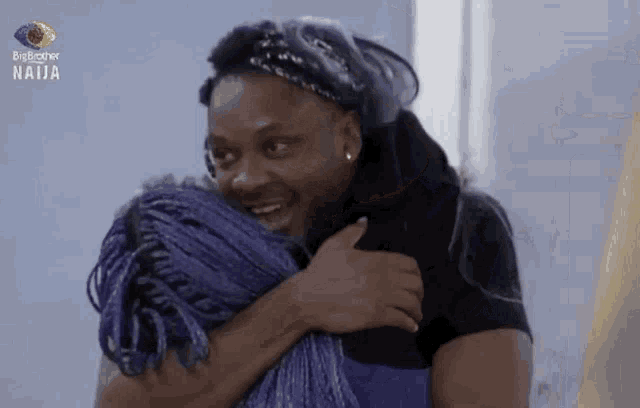 a man in a black shirt is hugging a woman with purple braids .
