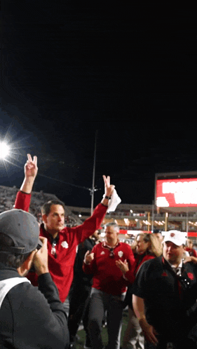 a man in a red jacket holds up his index finger in the air