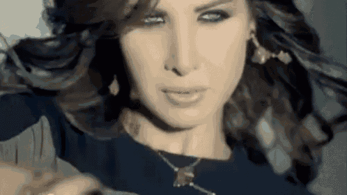 a woman wearing a necklace and earrings is looking at the camera .