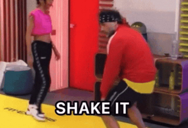 a man and a woman are standing on a yellow mat and the man is saying shake it