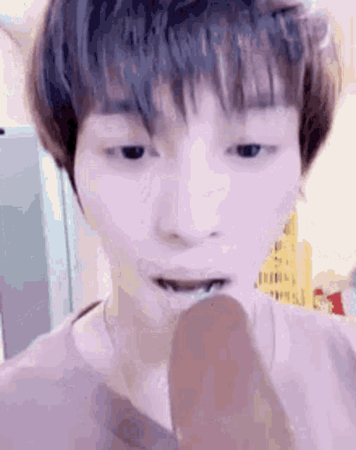 a young man is brushing his teeth with a toothbrush while eating an ice cream bar .