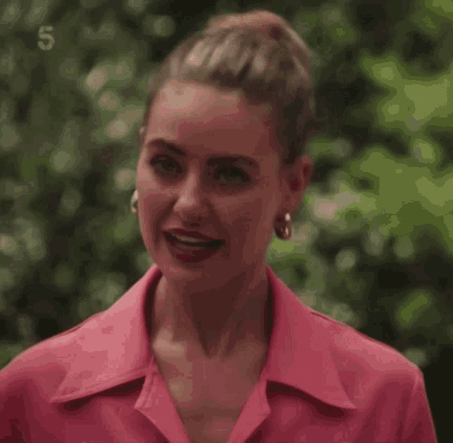 a woman in a pink shirt is looking at the camera with the number 5 behind her