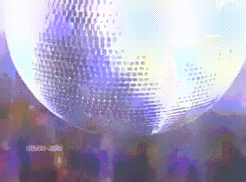 a disco ball is hanging from the ceiling in a dark room with people standing around it .