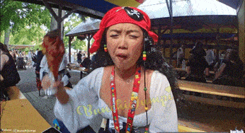 a woman in a pirate costume is holding a piece of meat in front of a twitter logo