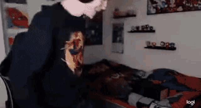 a man in a black shirt is standing in front of a bed in a room .