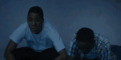 two men are sitting on the floor in the dark .