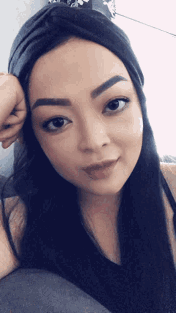 a woman wearing a black headband and a black tank top looks at the camera