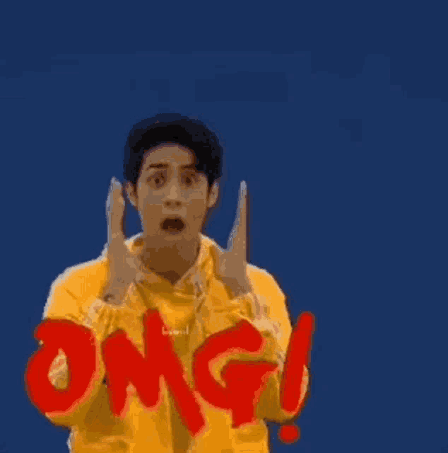 a man in a yellow hoodie is making a surprised face while holding his hands up in the air .