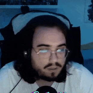 a man with a beard and glasses is wearing headphones and a hat .