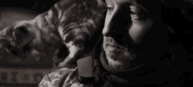 a man is holding a cat on his shoulder in a dark room .