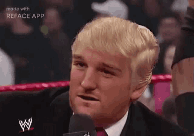 a man in a suit and tie is talking into a microphone in a ring .