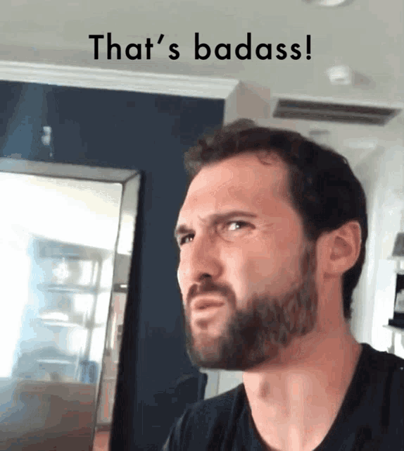 a man with a beard is making a funny face with the words that 's badass behind him