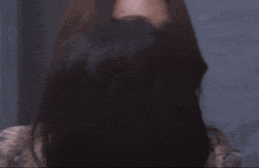 a woman with long hair is standing in front of a blue wall