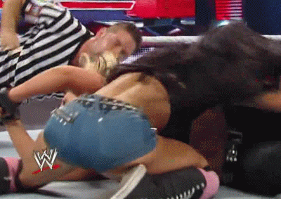 a woman in shorts is wrestling a man in a striped shirt in a wrestling ring .