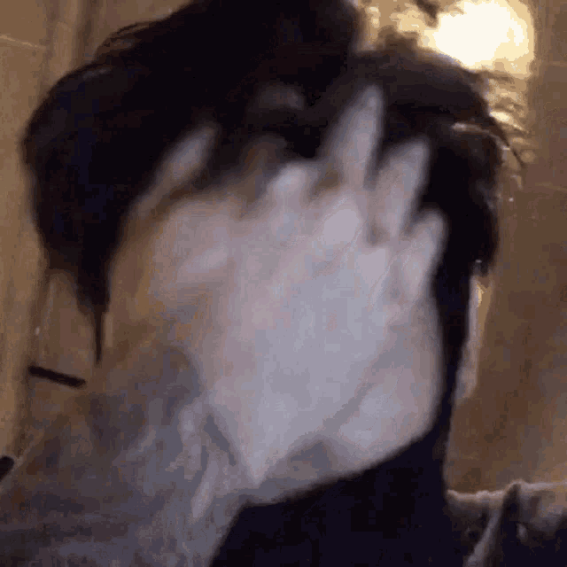 a close up of a person 's face with their hand on it .