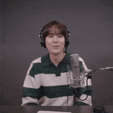 a man wearing headphones and a green and white striped sweater is standing in front of a microphone