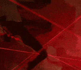 a person is surrounded by red laser beams in a dark area
