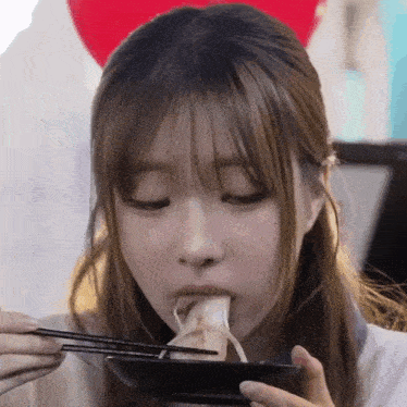 a girl is eating something with chopsticks from a plate