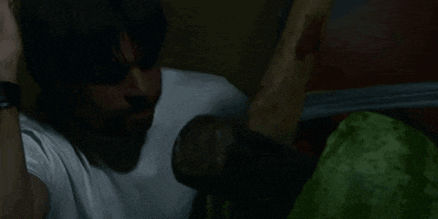 a man in a white shirt is holding a bloody bat in his hand .