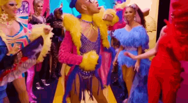 a group of drag queens are standing next to each other in colorful costumes .