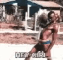 a woman in a bikini is standing in front of a house and saying hey girl .