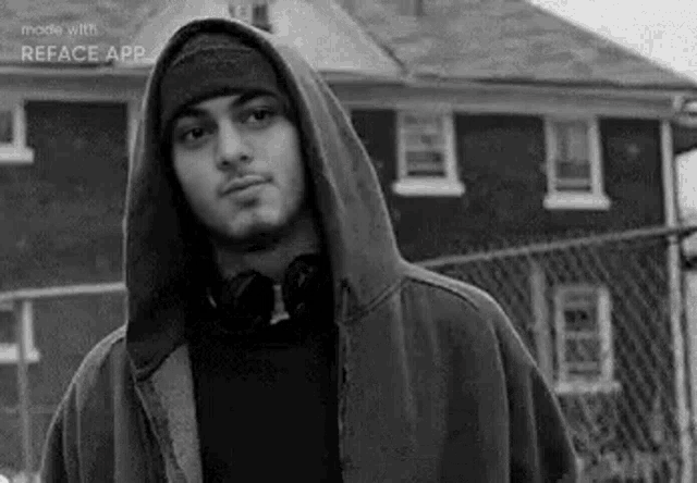 a black and white photo of a man wearing a hooded jacket and a beanie .