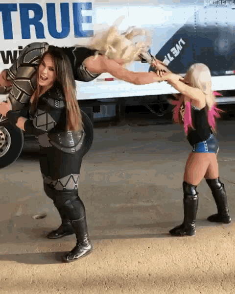 two women are standing in front of a truck that has the word true on it