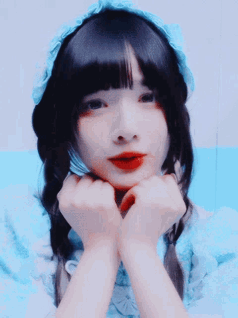 a girl with pigtails and a blue headband holds her hands to her face