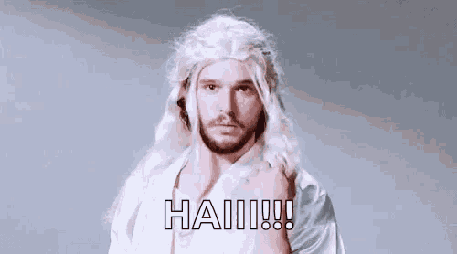 a man wearing a white wig and a white shirt is standing in front of a gray background .