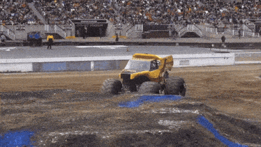 a monster truck is driving on a dirt track in front of a stadium that says gmc stadium
