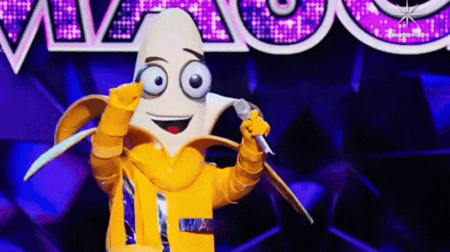 a person dressed as a banana is holding a microphone and smiling on a stage .