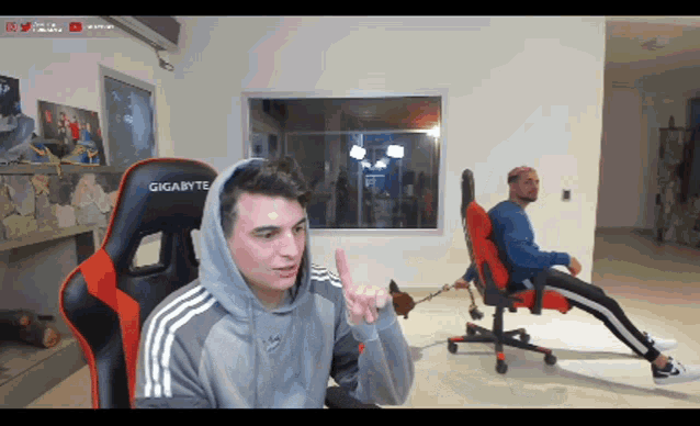 a man in a hoodie is sitting in a gigabyte chair