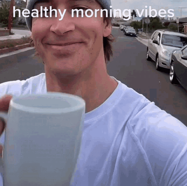 a man holding a coffee mug with the words healthy morning vibes written on the bottom